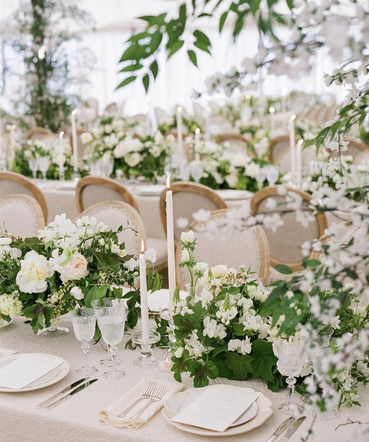 the table is set with white flowers and greenery for an elegant wedding reception or special event