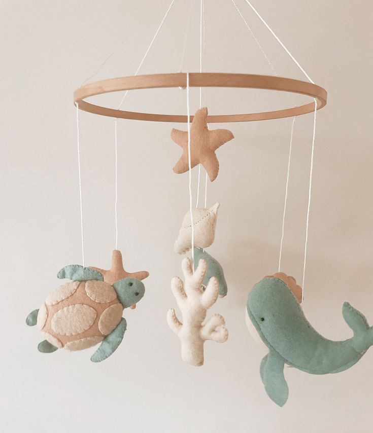 three sea animals hanging from a wooden mobile with starfish, turtle and dolphin decorations