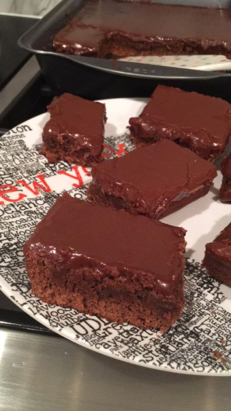 several pieces of chocolate cake on a plate next to a pan with one slice missing