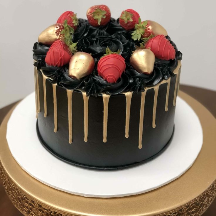 a chocolate cake with strawberries and chocolate drizzles on top, sitting on a gold plate