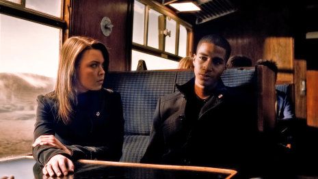 a man and woman sitting on a train looking at something