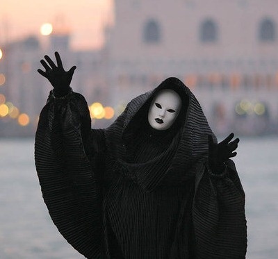 a person wearing a black mask and holding their hands up in the air