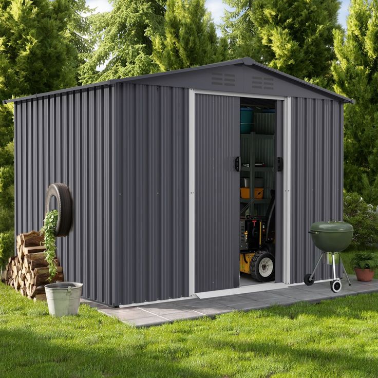 a small metal storage shed in the middle of a grassy area with a wheelbarrow next to it