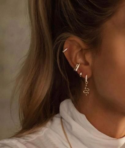 a close up of a person wearing earrings and a white t - shirt with the word love written on it