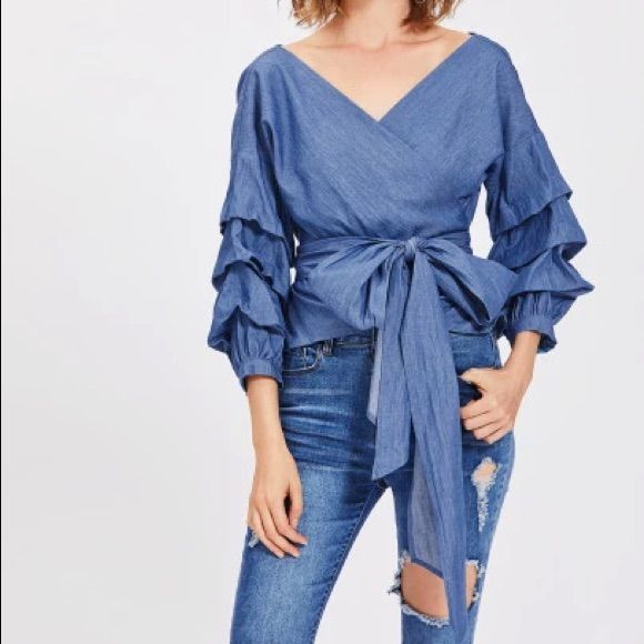 Gathered-Sleeve Denim Wrap Top With Off The Shoulder Fit. 100% Cotton Chic V-neck Denim Top For Spring, Chic Spring Denim V-neck Top, Trendy Medium Wash Blouse For Spring, Denim Blue Blouse For Fall Day Out, Denim Blue Blouse For Day Out In Fall, Fall Denim Blue Blouse For Day Out, Spring V-neck Denim Blue Top, Chic V-neck Denim Top, Chic Blue V-neck Denim Top