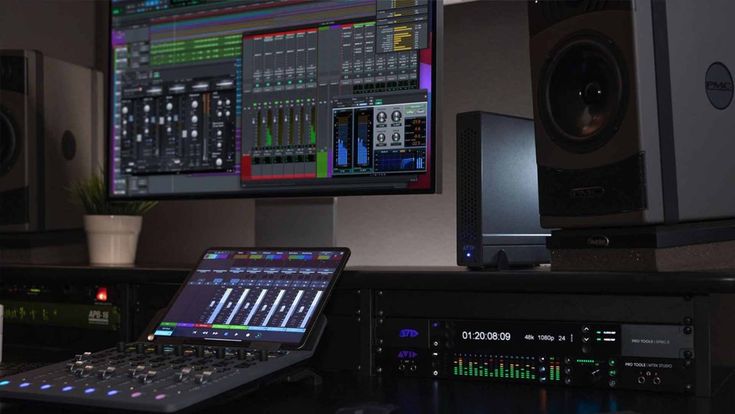 a laptop computer sitting on top of a desk next to sound mixing equipment in front of a monitor