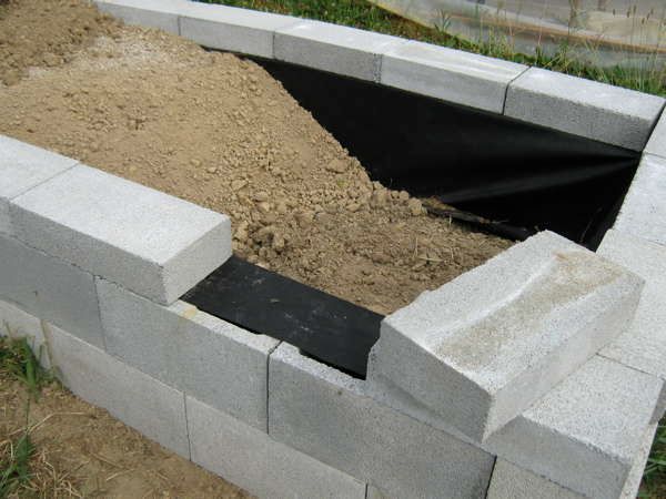 a cement fire pit is being built into the ground with concrete blocks surrounding it and grass in the background