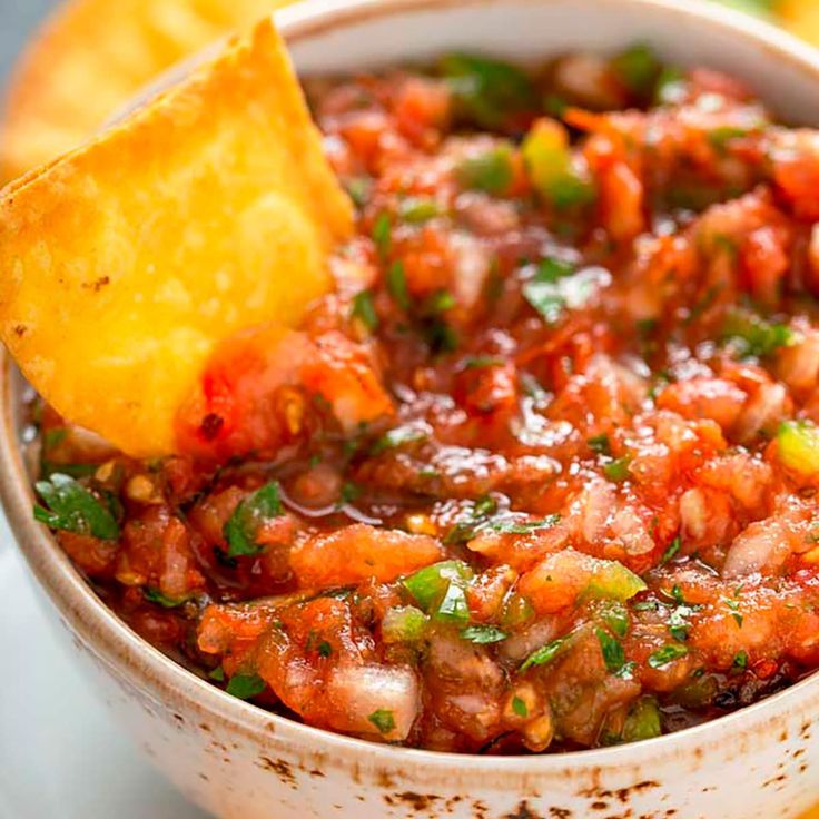 a close up of a bowl of food with a tortilla chip in it