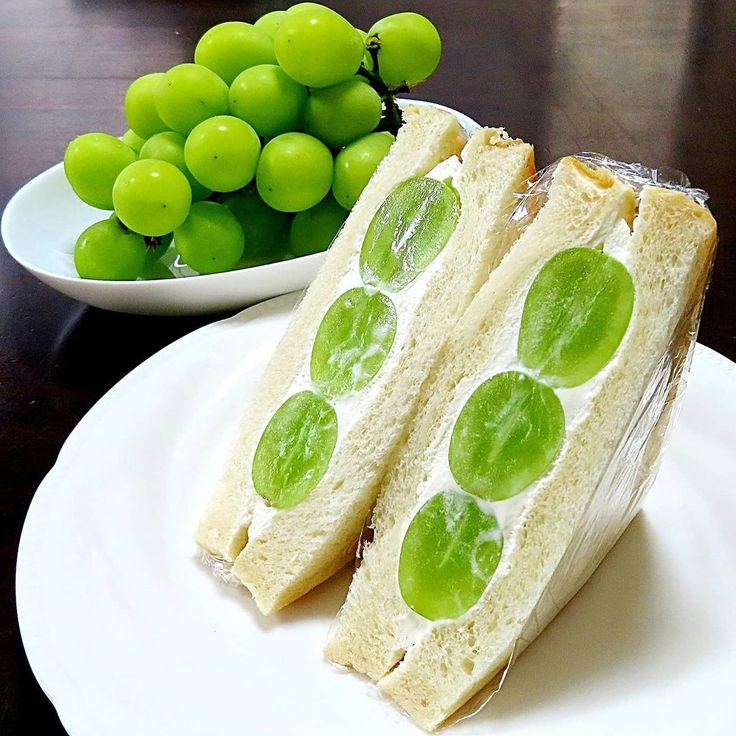 there is a sandwich with green grapes on the side