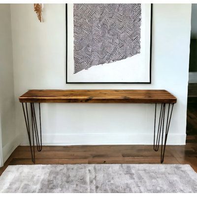 a wooden table with hairpin legs in front of a white wall and rug on the floor