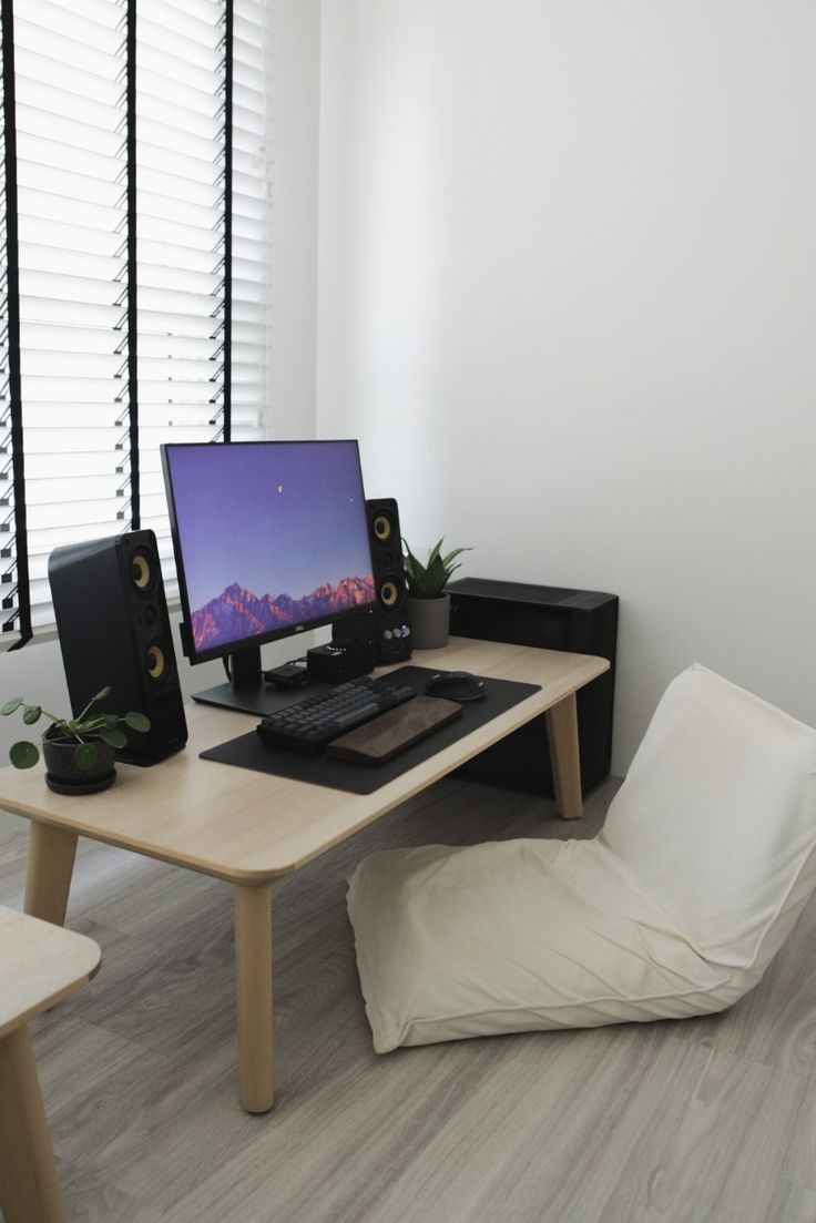 there is a computer on the desk with speakers and a pillow in front of it