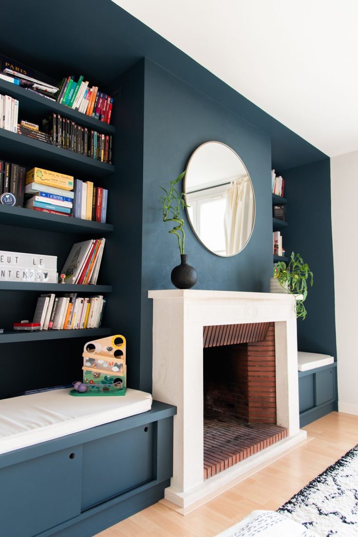 a living room filled with furniture and a fire place under a round mirror on the wall