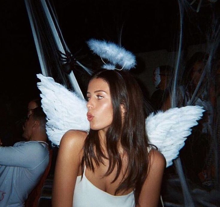 a woman with angel wings standing in front of some people at a party or event