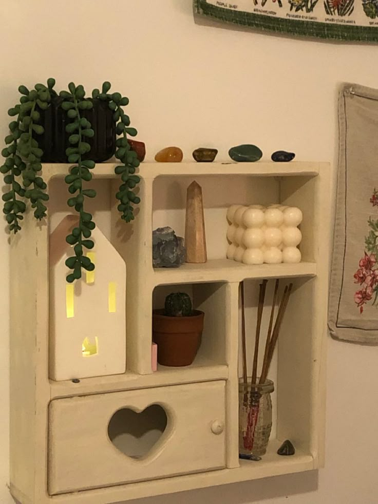 a white shelf with plants and other items on it