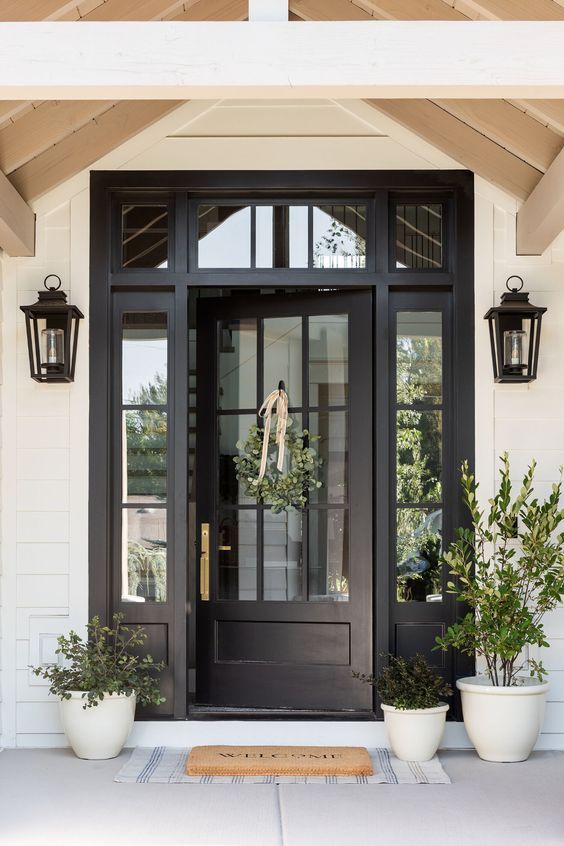 a black front door with two potted plants on the side and an instagram post about it