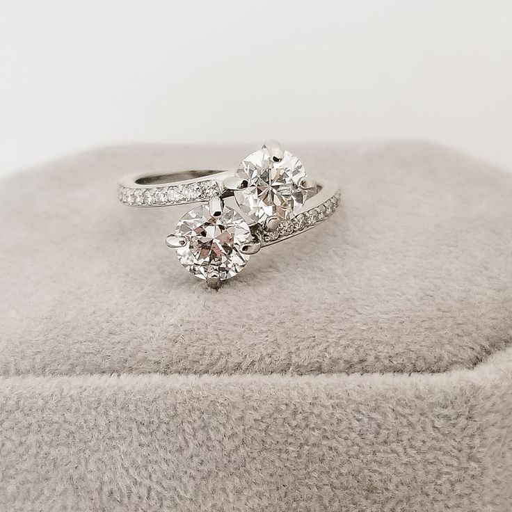 two diamond rings sitting on top of a cushioned surface with white furnishing