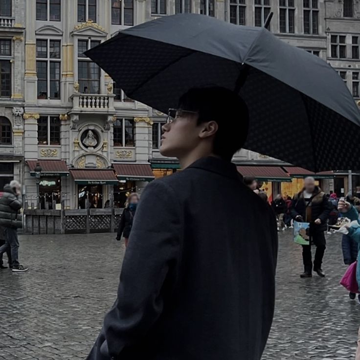 a man holding an umbrella in the middle of a busy city square with people walking around