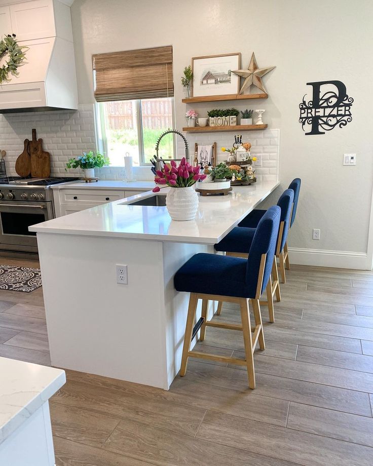 a kitchen with white counter tops and blue chairs