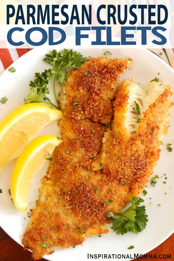 parmesan crusted fish fillets on a white plate with lemon wedges