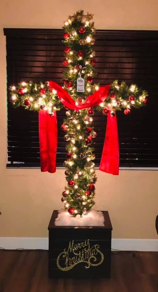 a lighted christmas cross with red bows and lights in the shape of a jesus's crucifix