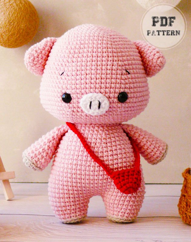 a pink crocheted teddy bear with a red ribbon around it's neck