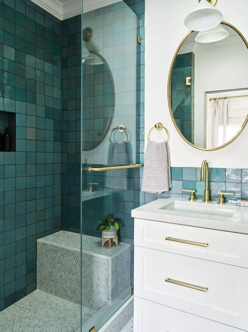 a bathroom with blue tiles and gold fixtures, including a shower stall that has a mirror above it