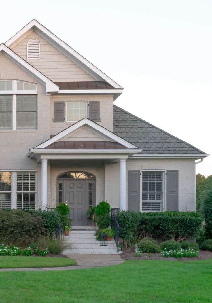 a large house with lots of windows and bushes in front of the entrance to it