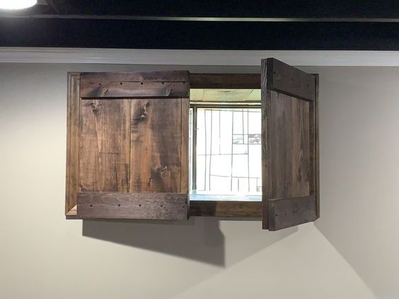 an open window in the corner of a room with white walls and wooden shutters