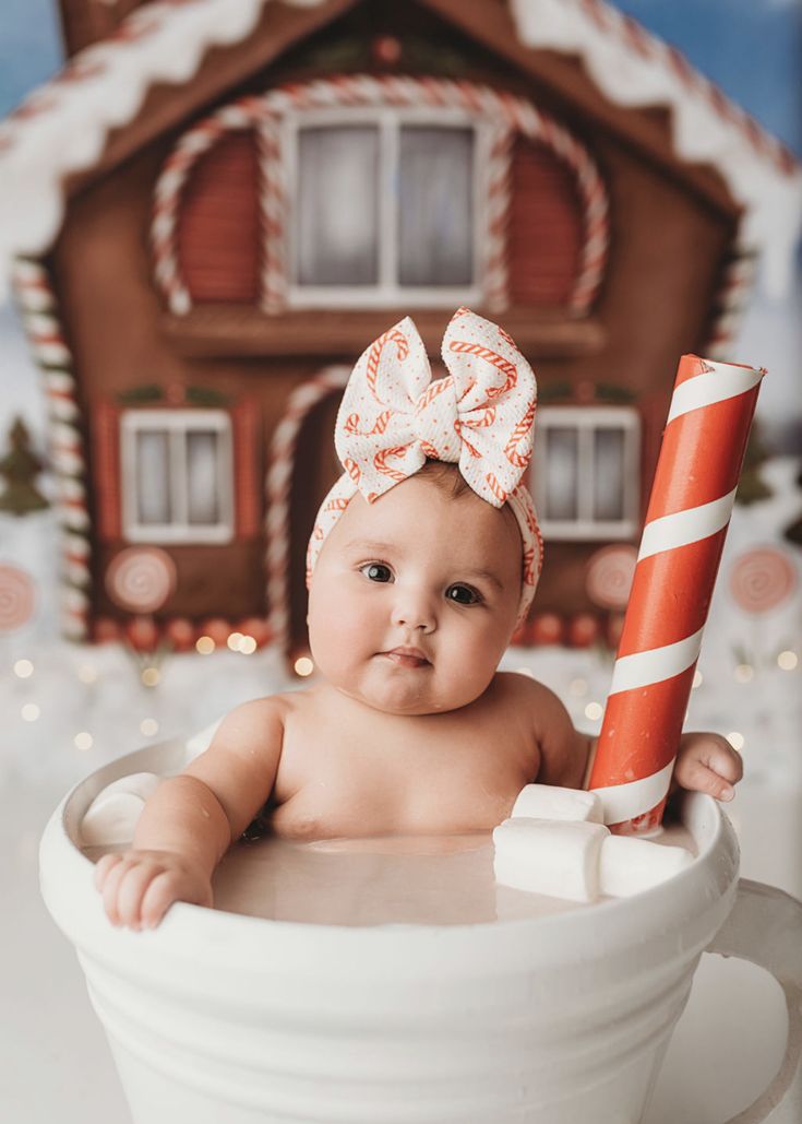 a baby is sitting in a cup with a candy cane on it's head