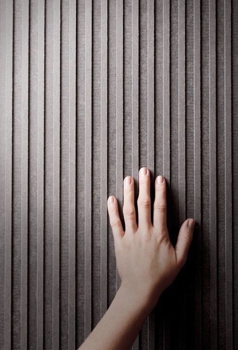 a person's hand on the wall with vertical blinds