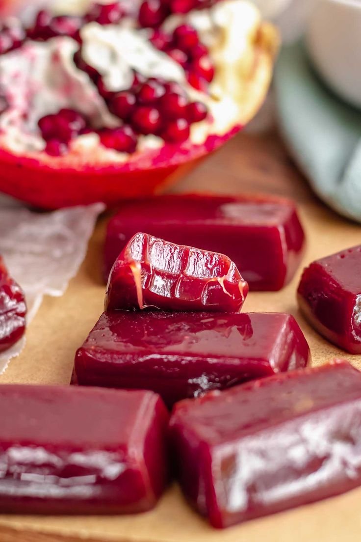 pieces of beet sit on a cutting board next to a pomegranate