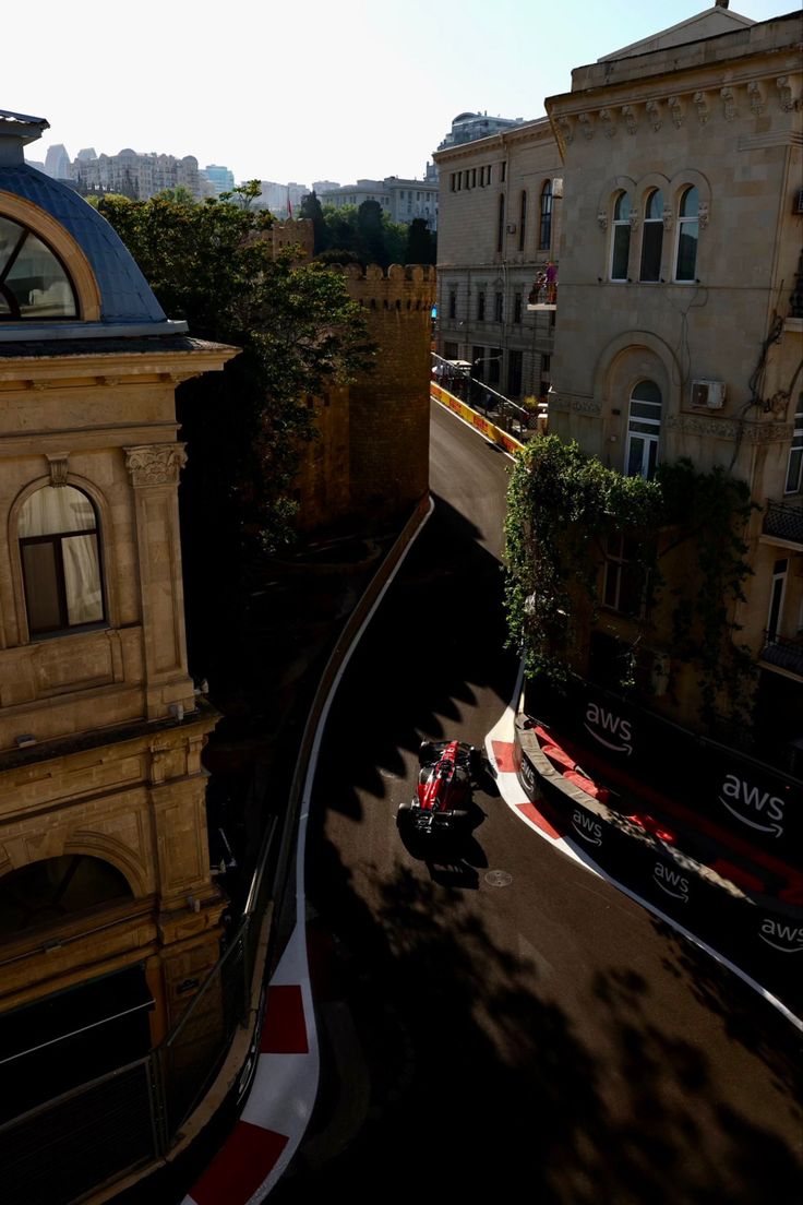 an aerial view of a race track with cars driving on it and buildings in the background