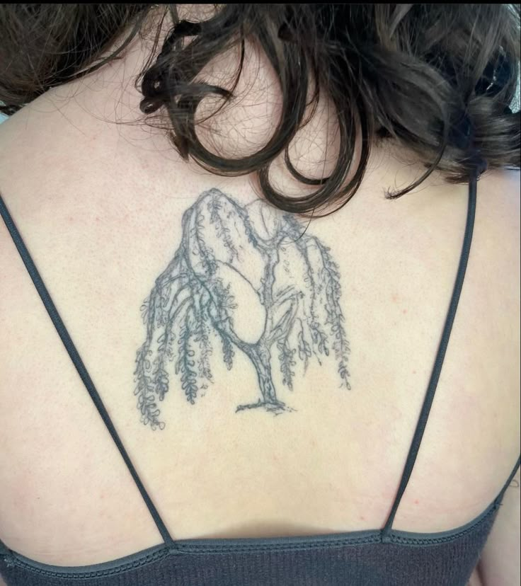 the back of a woman's shoulder with a tree tattoo on her upper arm