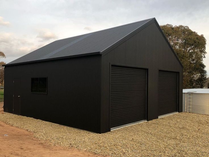 a large black building sitting on top of a dirt field