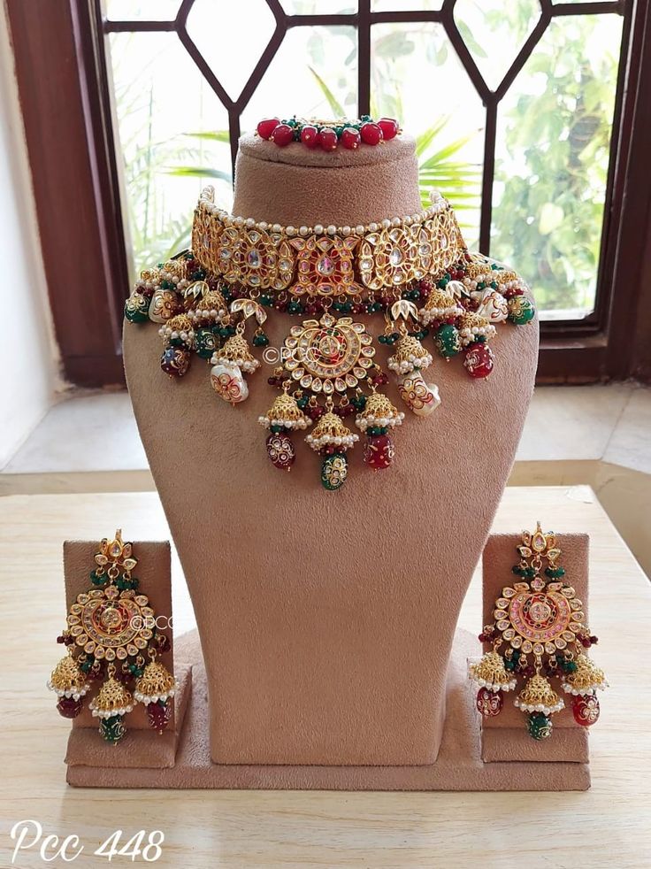 an elaborate necklace and earring set on display in front of a window with windowsill