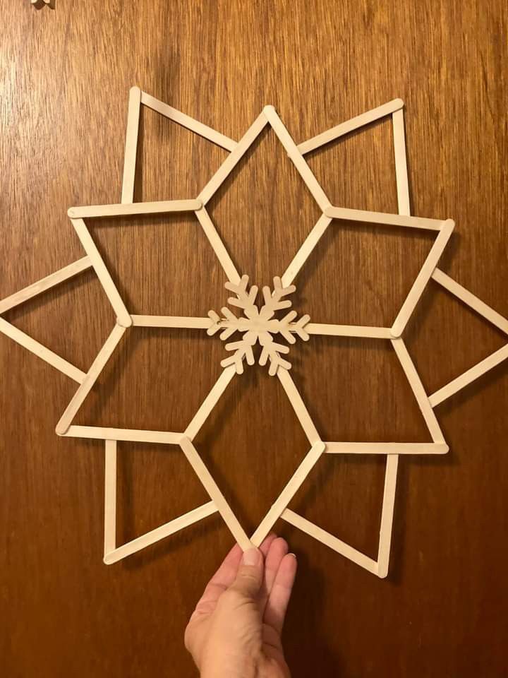 someone is making a snowflake out of popsicle sticks