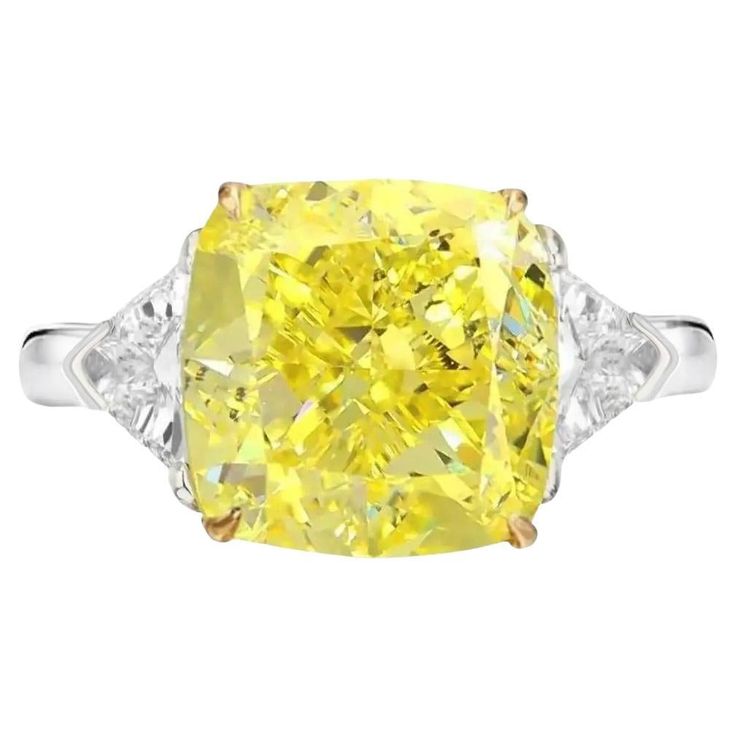 a fancy yellow diamond ring with three pear shaped diamonds on the sides and four prongs