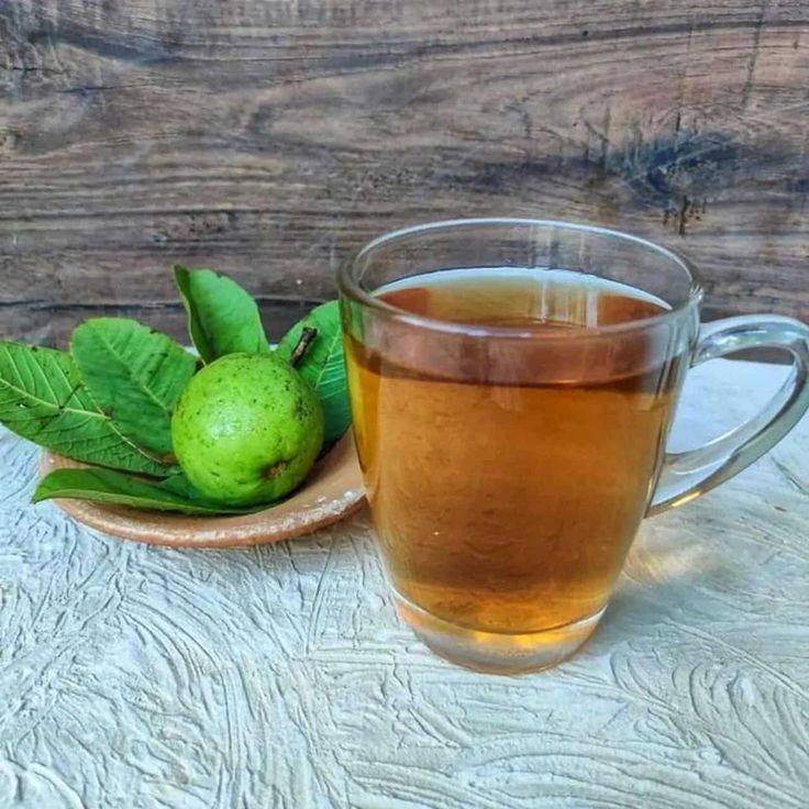 a cup of tea next to some green leaves