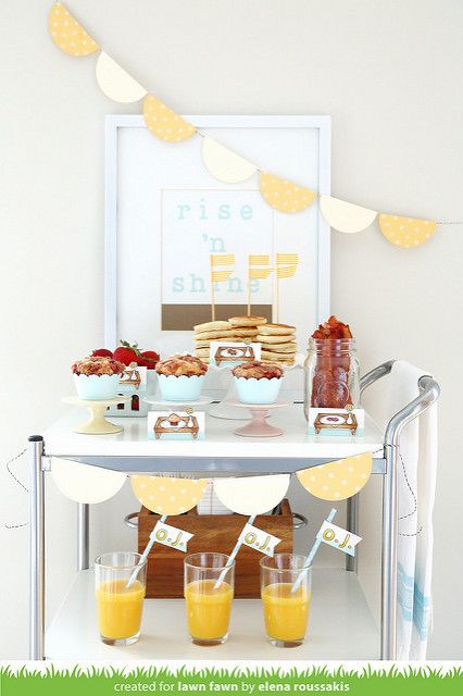 a table filled with food and drinks on top of a grass covered field next to a white wall