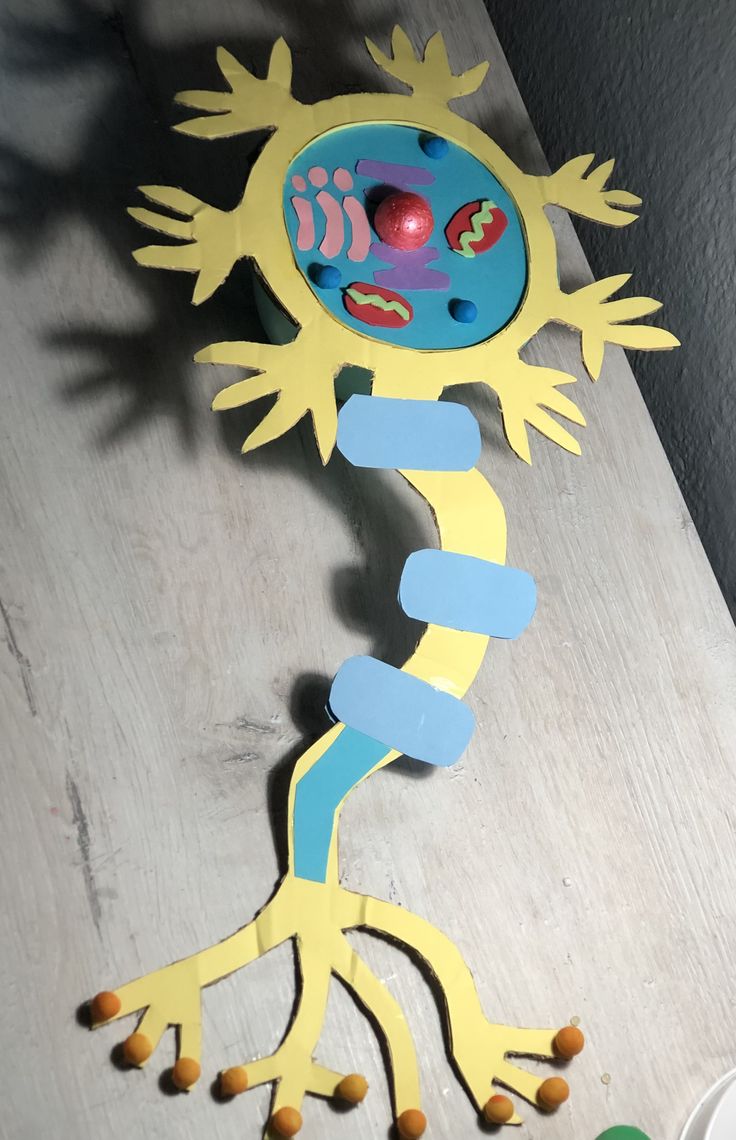 a paper cut out of a gecko with eyes and legs, standing on the floor