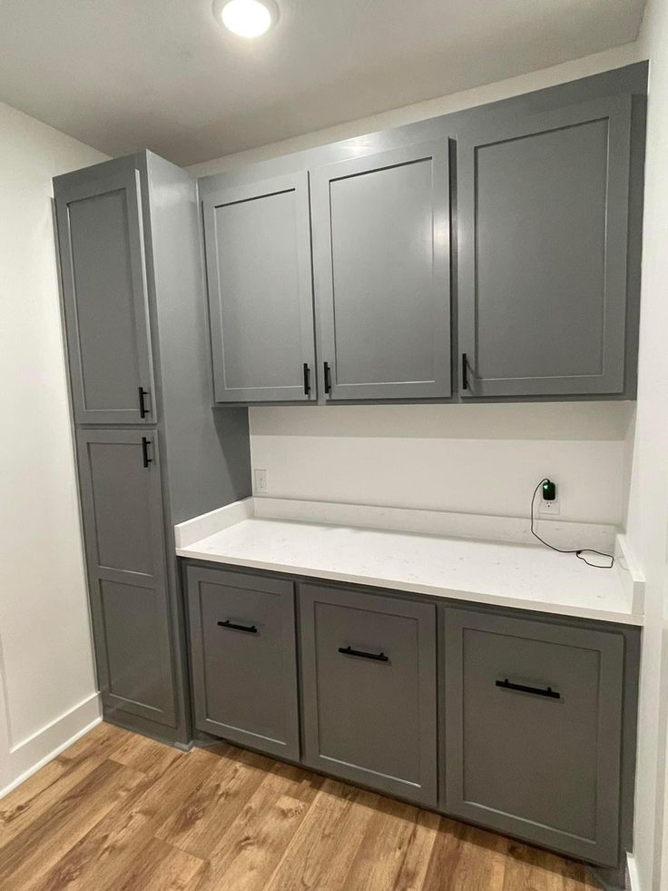 an empty kitchen with gray cabinets and white counter tops