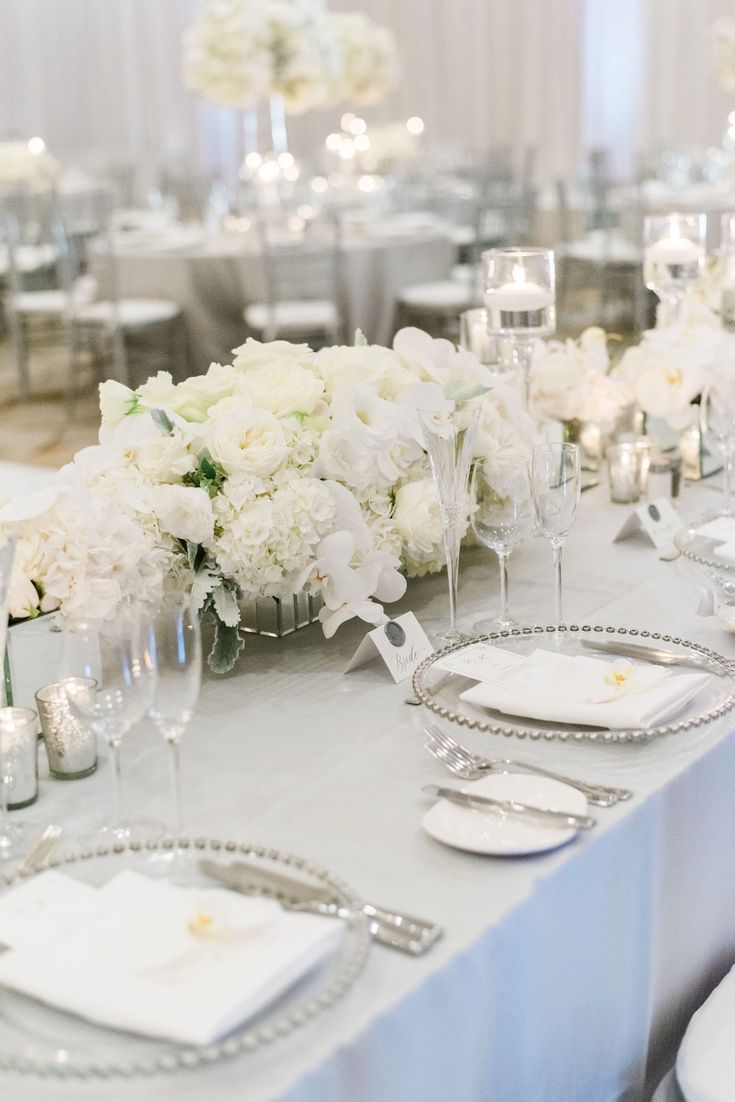 the table is set with silverware and white flowers