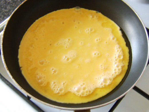 an omelet is being cooked in a pan on top of the gas stove