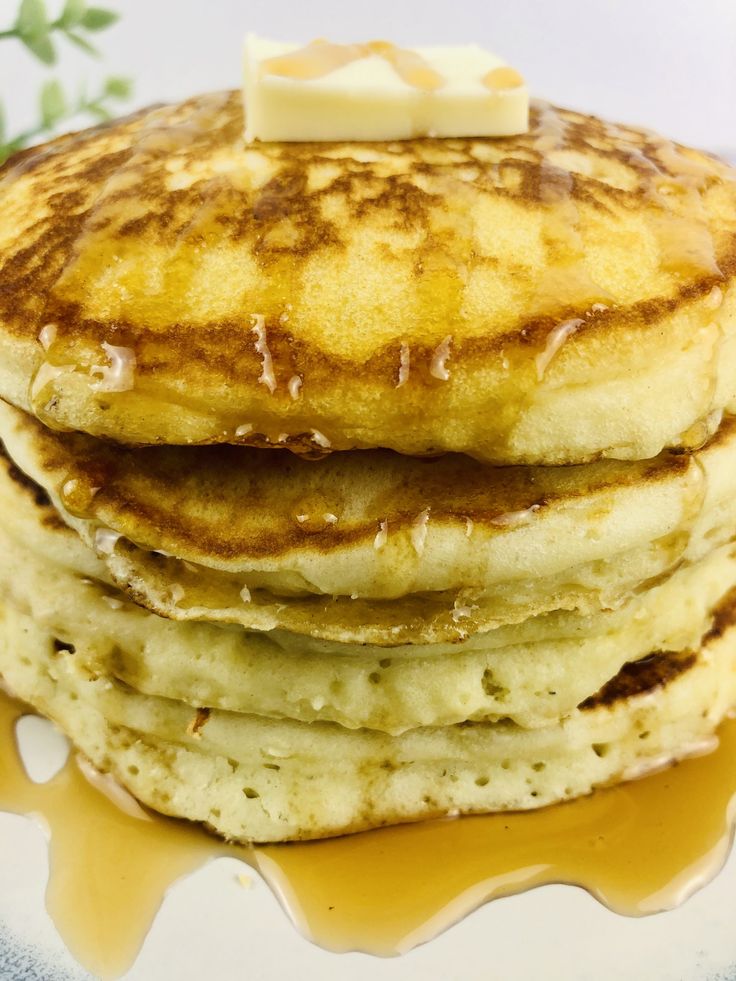 a stack of pancakes with butter on top and syrup drizzled around them