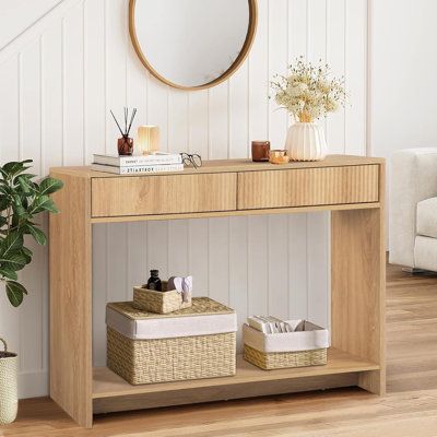 a wooden table with baskets under it and a round mirror above the table on top