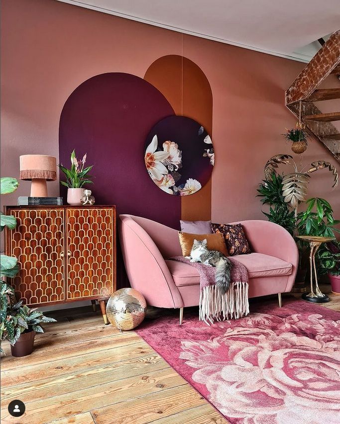 a living room with pink couches and rugs in front of a purple wall