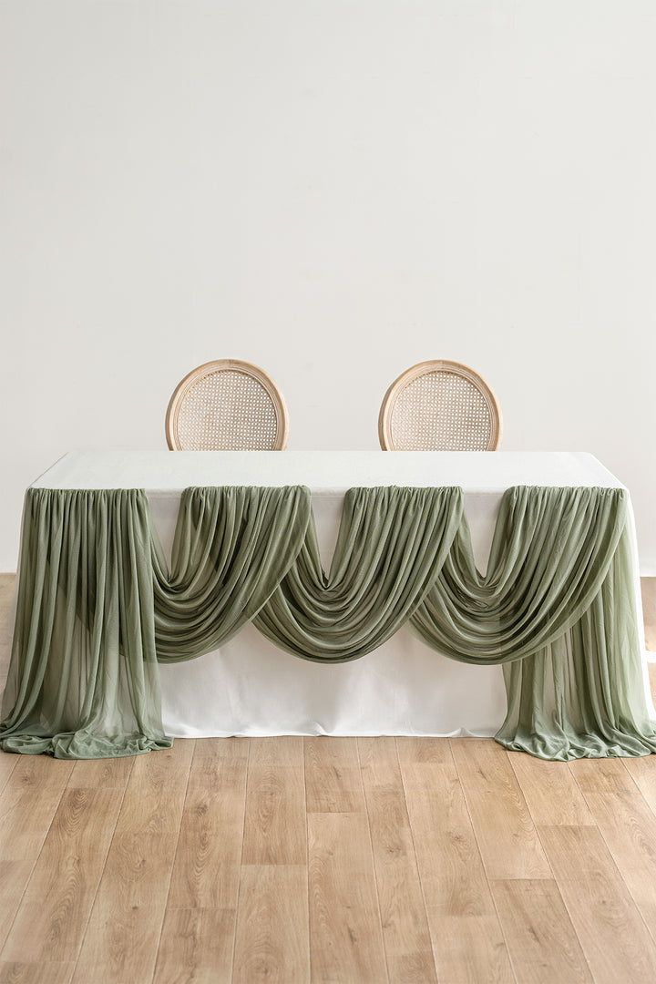 two chairs sitting on top of a wooden floor next to a table covered in green drapes