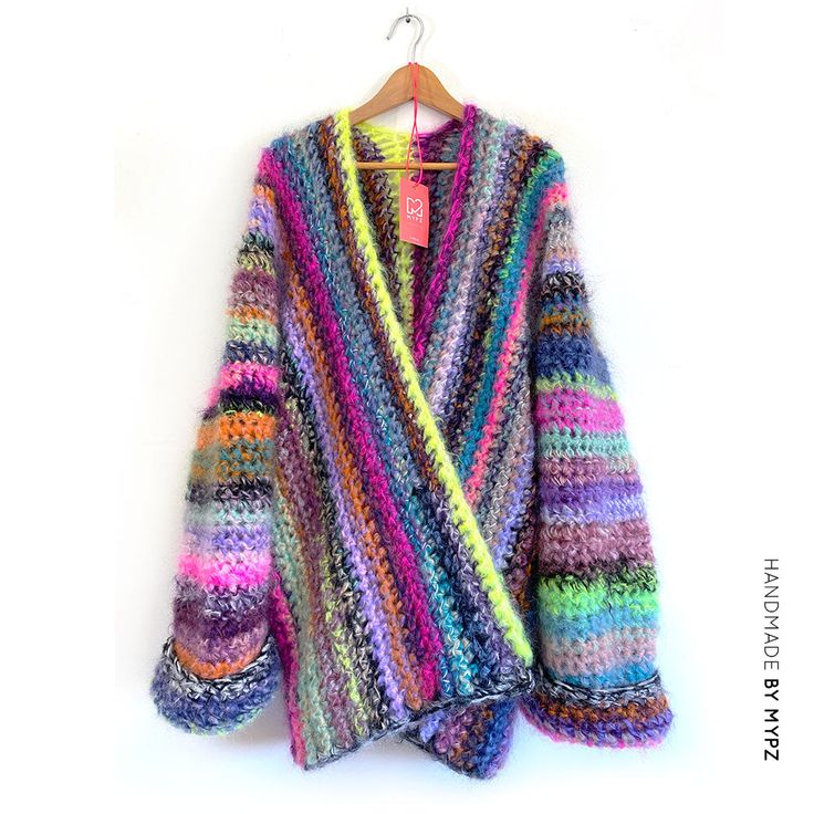 a multicolored cardigan sweater hanging on a hanger with a white wall in the background