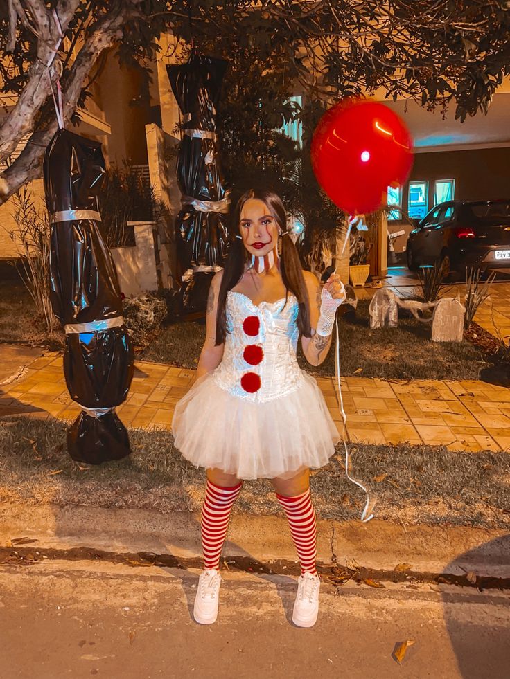 a woman dressed as a clown holding a red balloon and wearing a white tutu