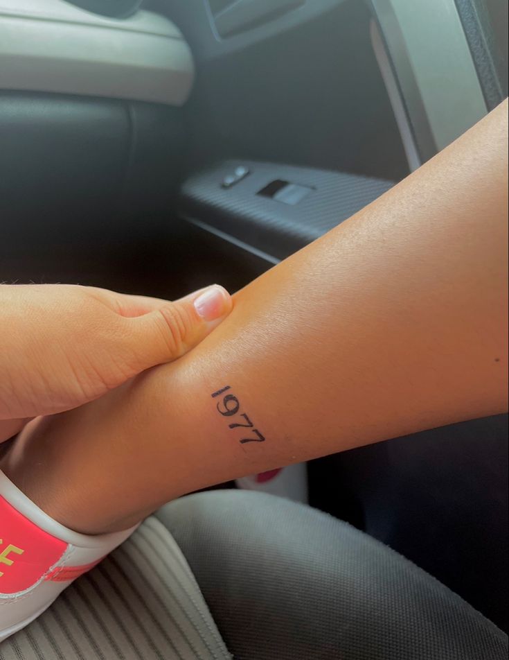 a woman's foot with the word love tattooed on her left leg in a car